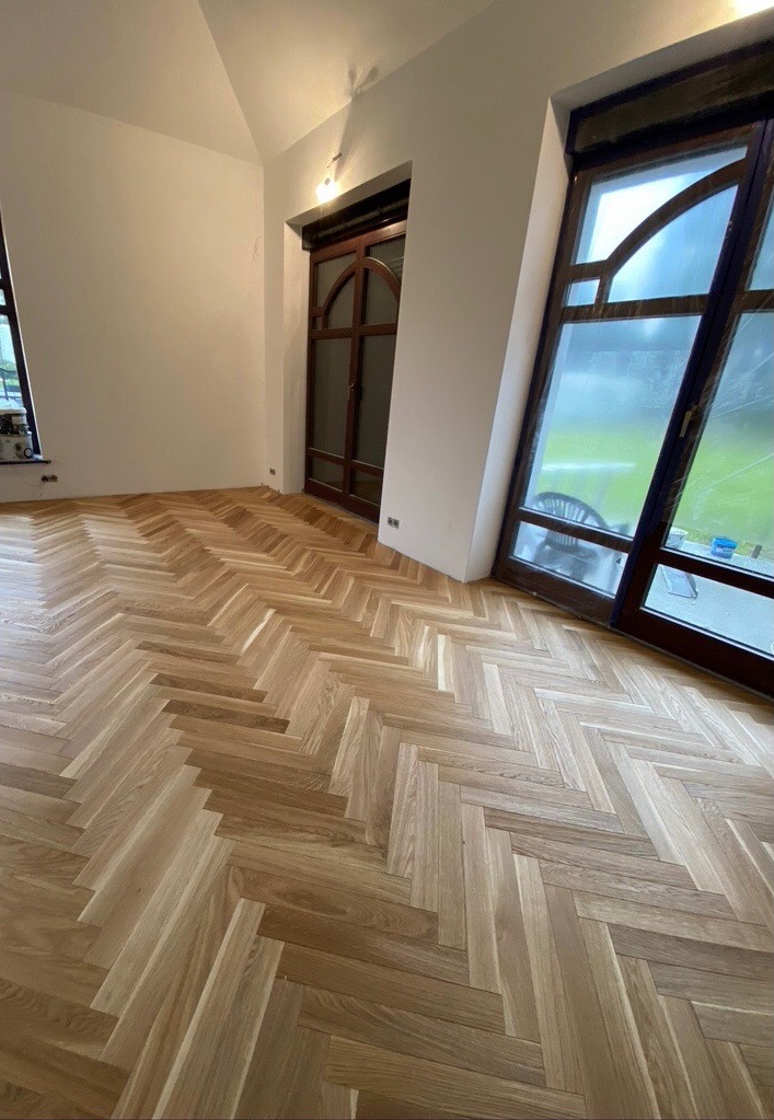 Fiskebeinsgulv i stue med buevinduer